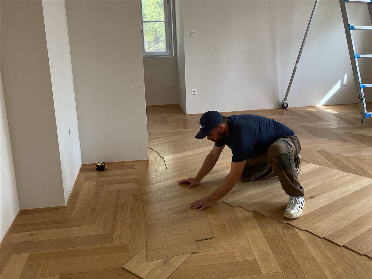 Handwerker verlegt Laminat-Parkett in einem hellen, renovierten Raum